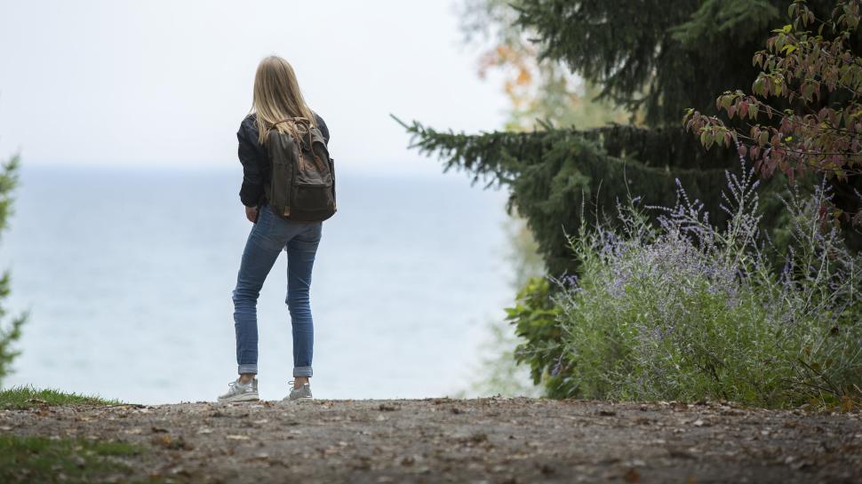 Free Image of Person with backpack looking out at serene lake view 