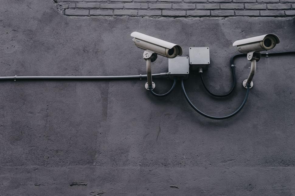 Free Image of Two surveillance cameras mounted on a gray walls 