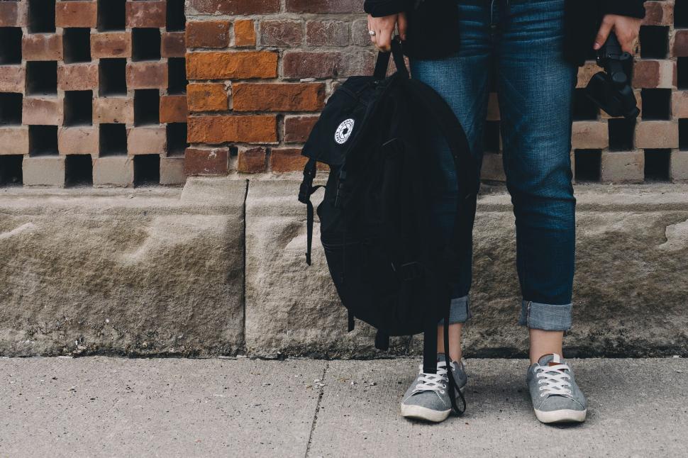 Free Image of Street-style casual outfit with backpack on brick wall 