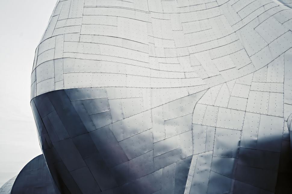 Free Image of Curved metallic structure with textured surfaces and bolts. 