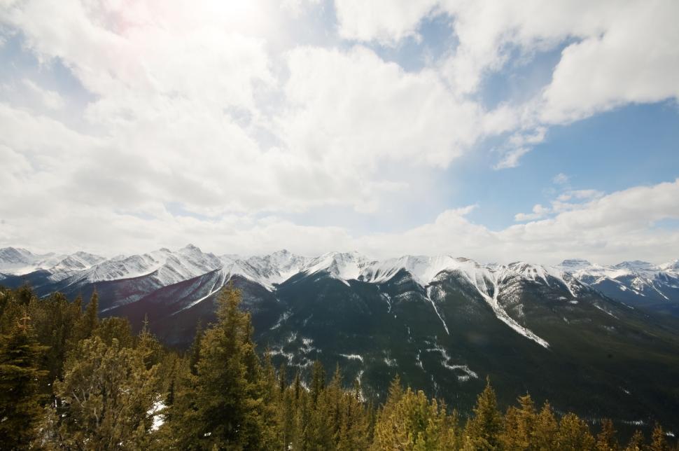 Free Image of Snow-covered mountain range under a partly cloudy sky. 