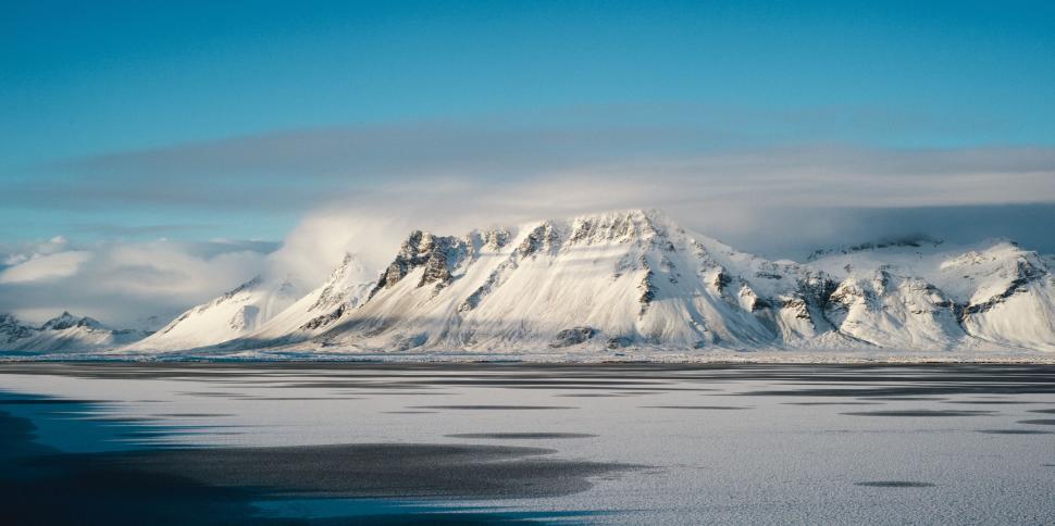 Free Image of Snowy mountain range under a blue sky with light clouds 