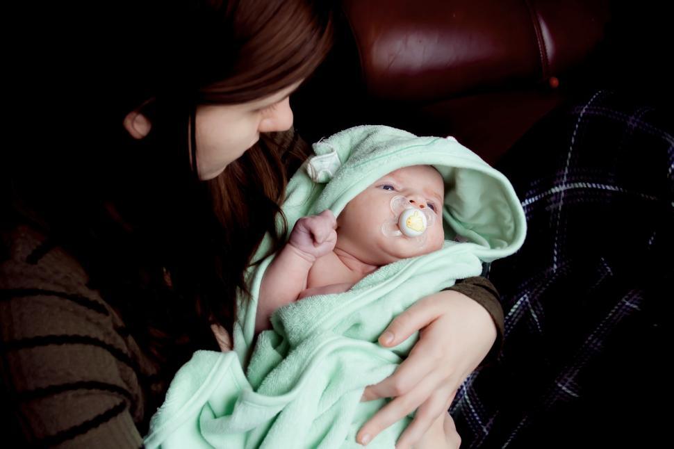Free Image of Mother holding newborn wrapped in green blanket 