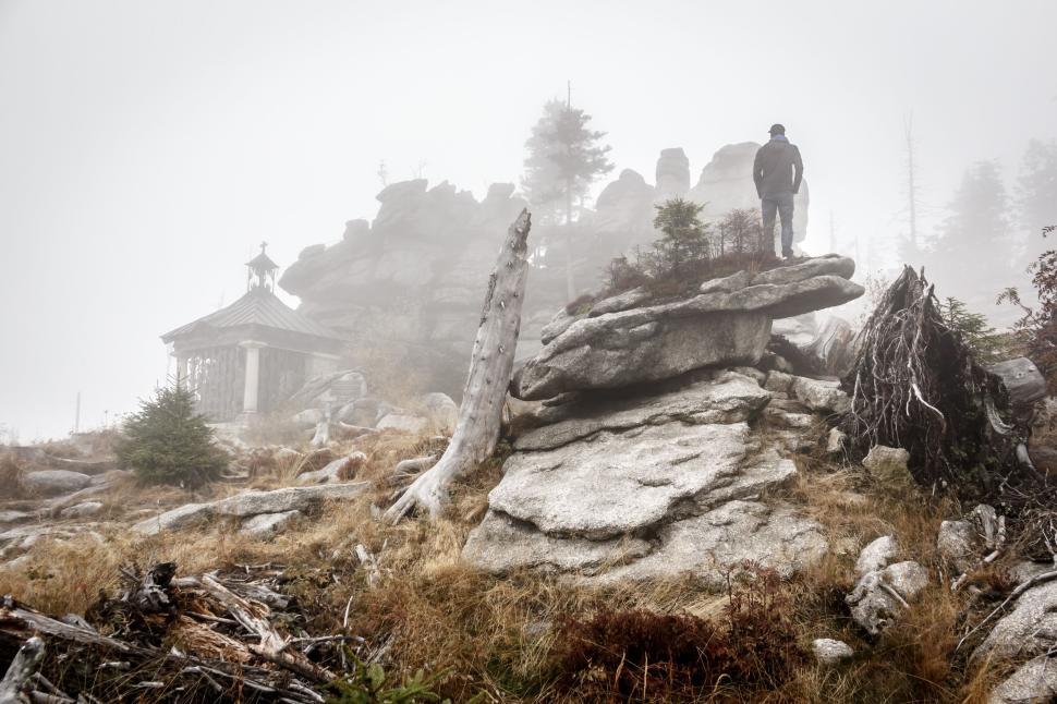 Free Image of Person standing on rocky terrain in fog near shrine 