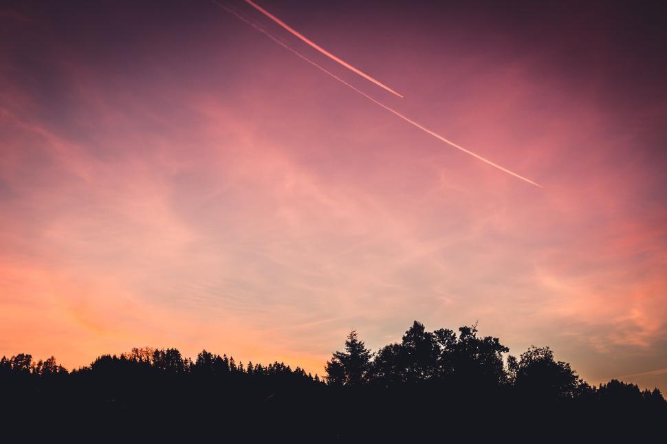 Free Image of Beautiful sunset sky with pink and purple hues, trees calm. 