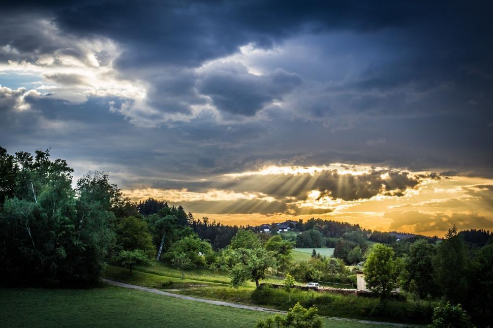 Free Image of Sunset illuminating cloudy sky over green hilly landscape. 