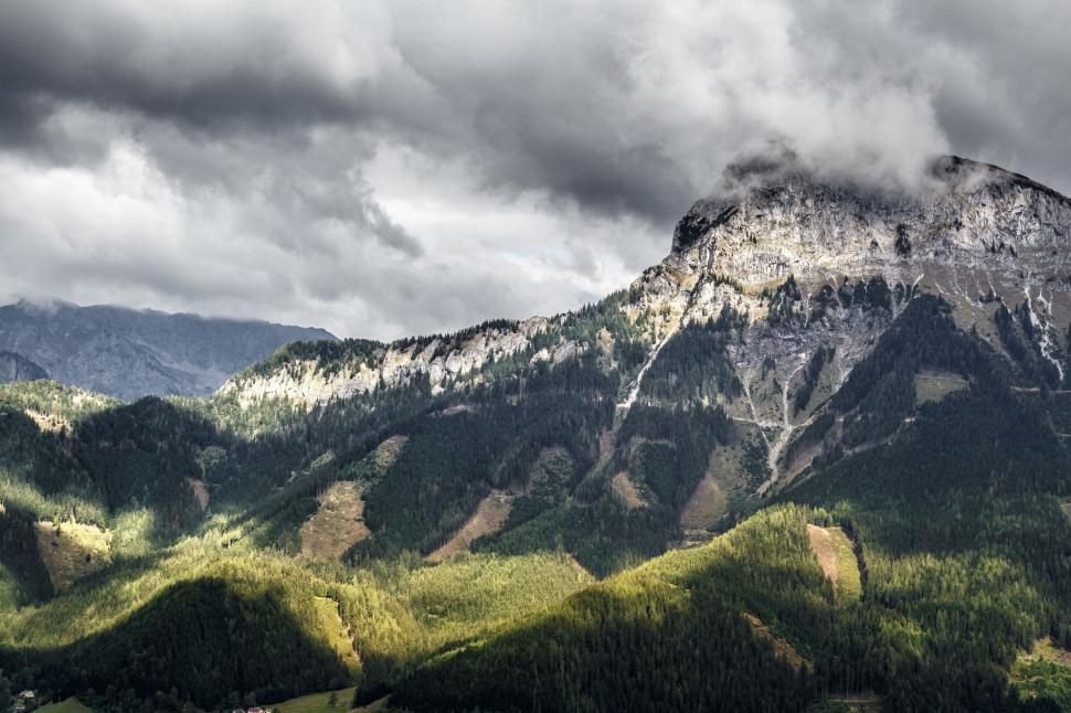 Free Image of Majestic mountain peak surrounded by dramatic cloudy sky. 