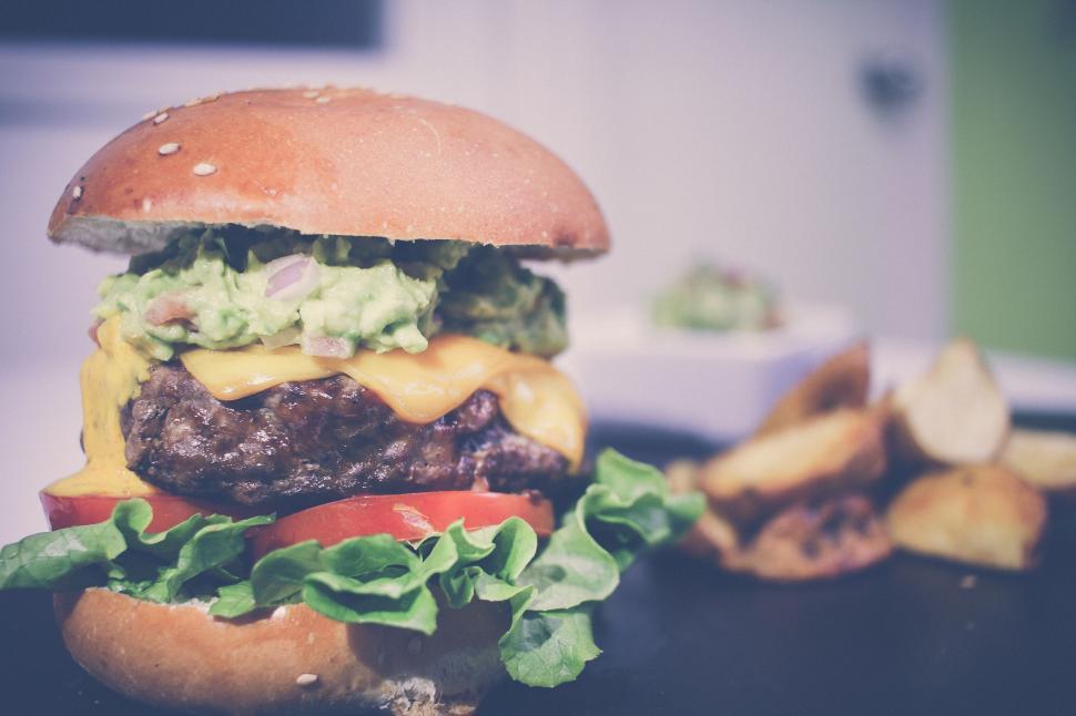 Free Image of Cheeseburger topped with guacamole served with fries 