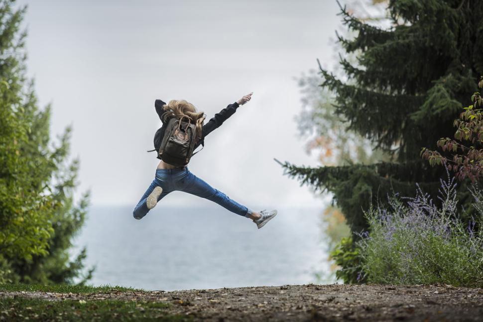 Free Image of Person jumps high with joy in the air, nature background 