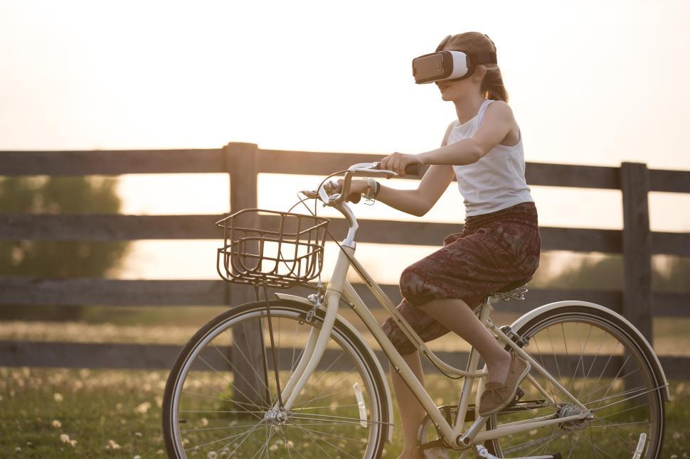 Free Image of Young girl with VR headset riding a bicycle outdoors 