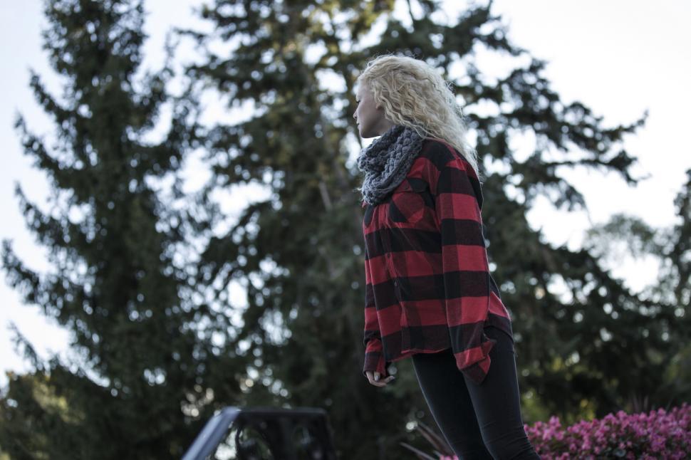 Free Image of Person in red plaid shirt standing amidst green trees 