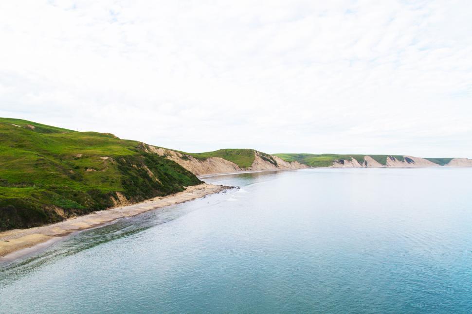 Free Image of Tranquil coastline with green hills and clear waters. 