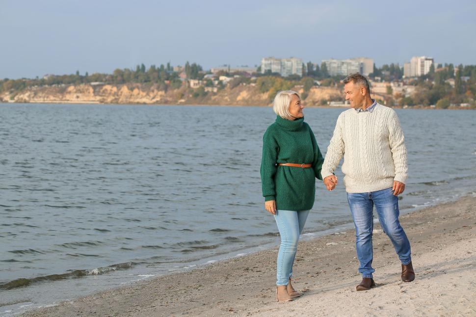 Free Image of Couple walking hand in hand along a beachfront 