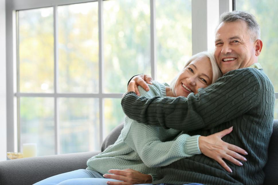 Free Image of Elderly couple hugging on a couch indoors brightly. 