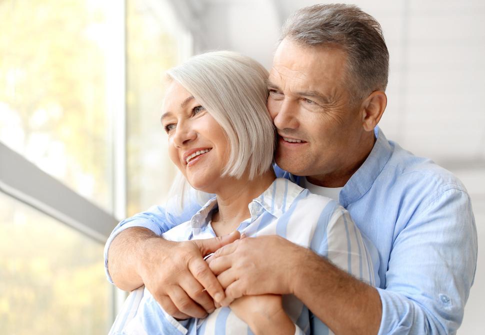 Free Image of Elderly couple embracing indoors with big windows. 