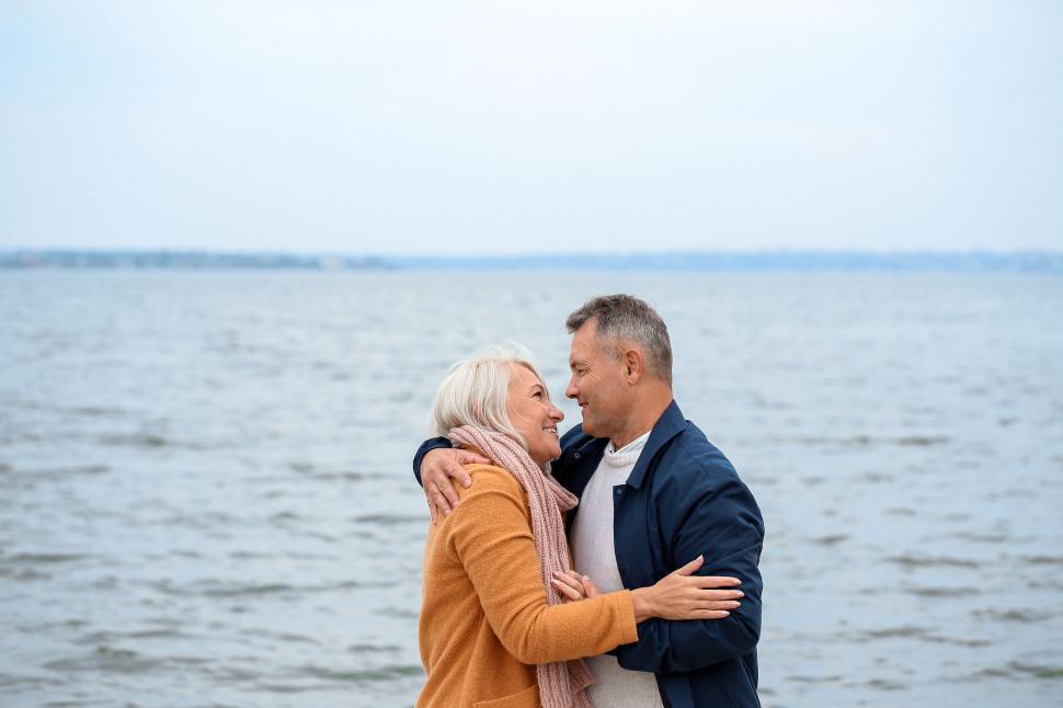 Free Image of Elderly couple embracing by the sea in warm clothes. 
