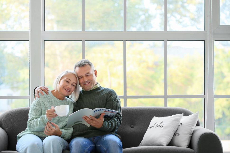 Free Image of Couple enjoying coffee and reading on a comfy sofa. 