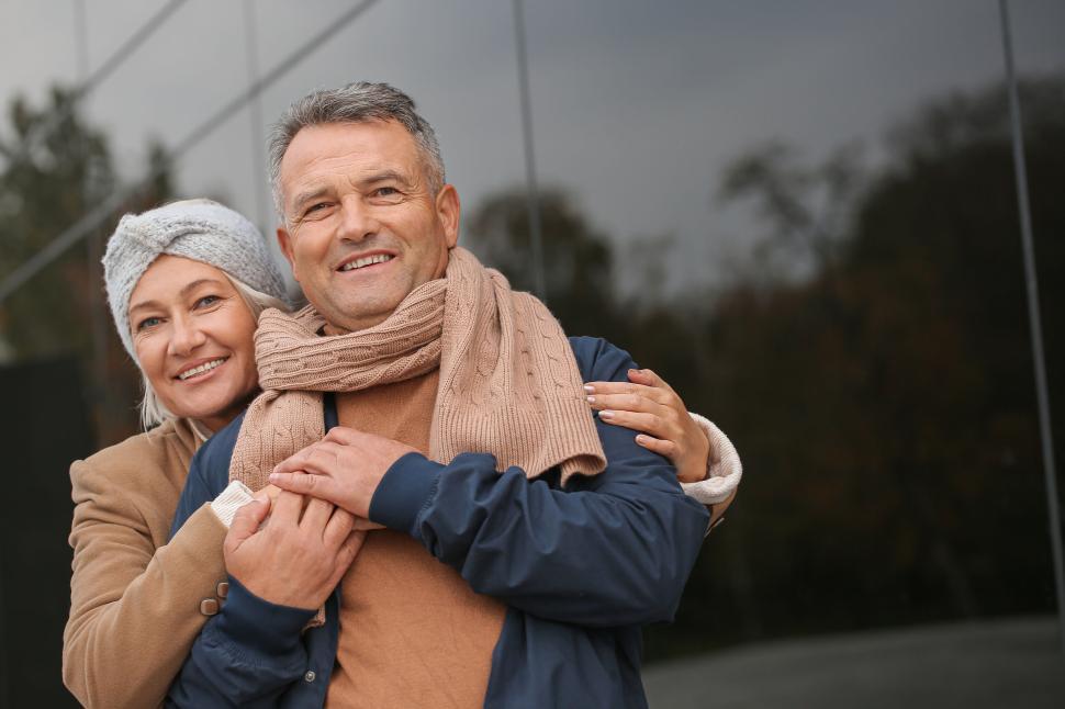 Free Image of Older couple warmly dressed embracing in the outdoors 