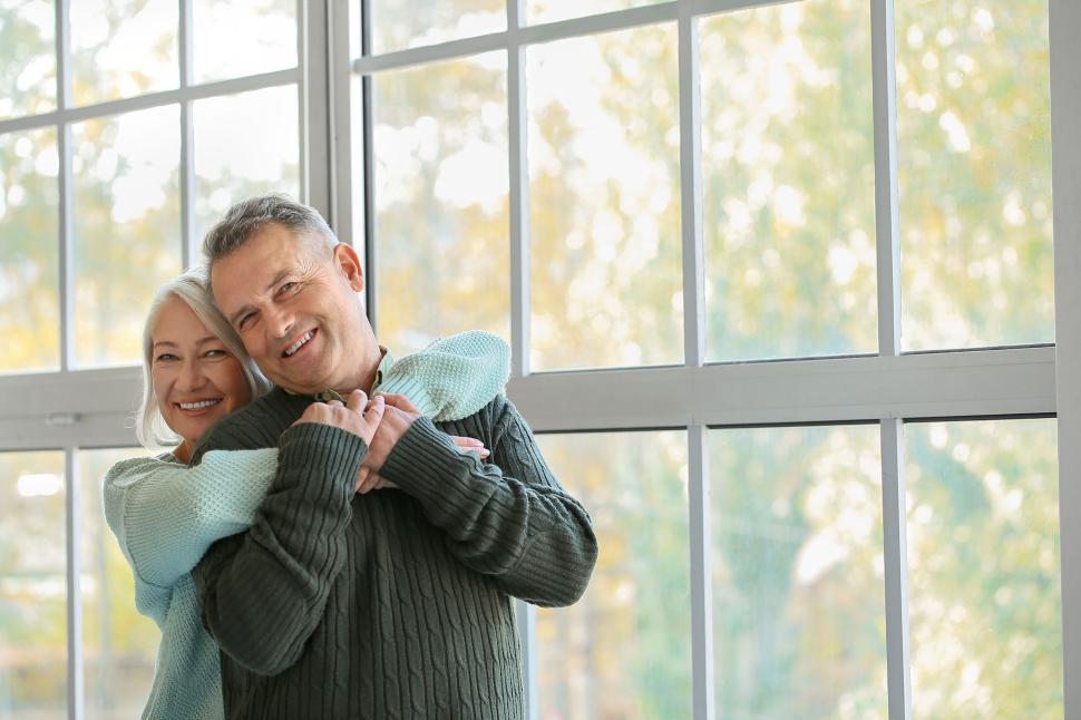 Free Image of Senior couple laughing and hugging by bright windows 