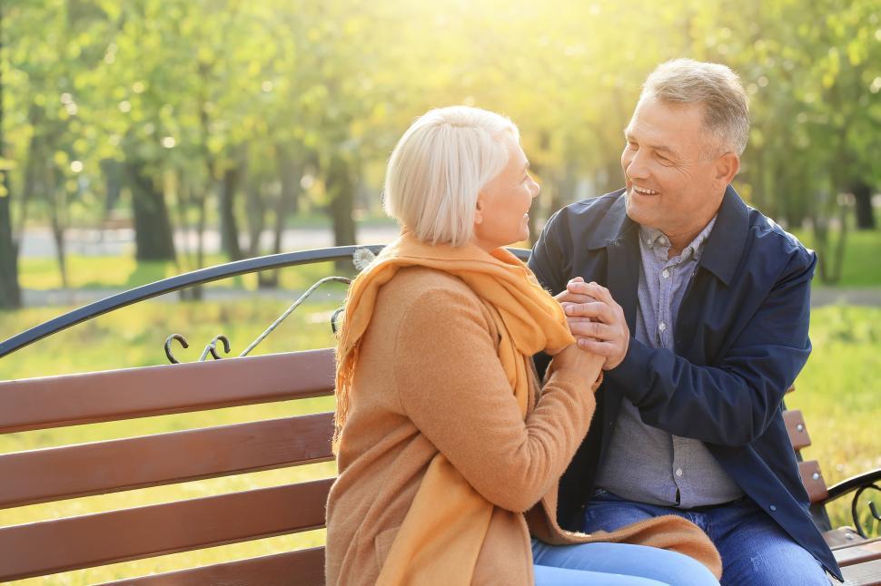 Free Image of Older couple enjoying talk on a bench in sunny park 