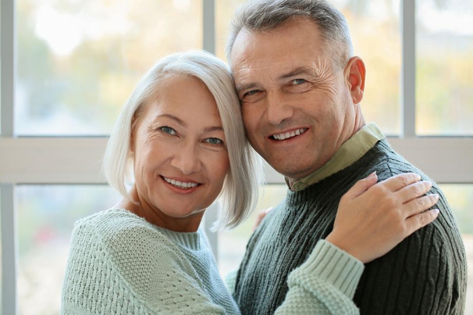 Free Image of Cheerful older couple hugging inside by window light. 
