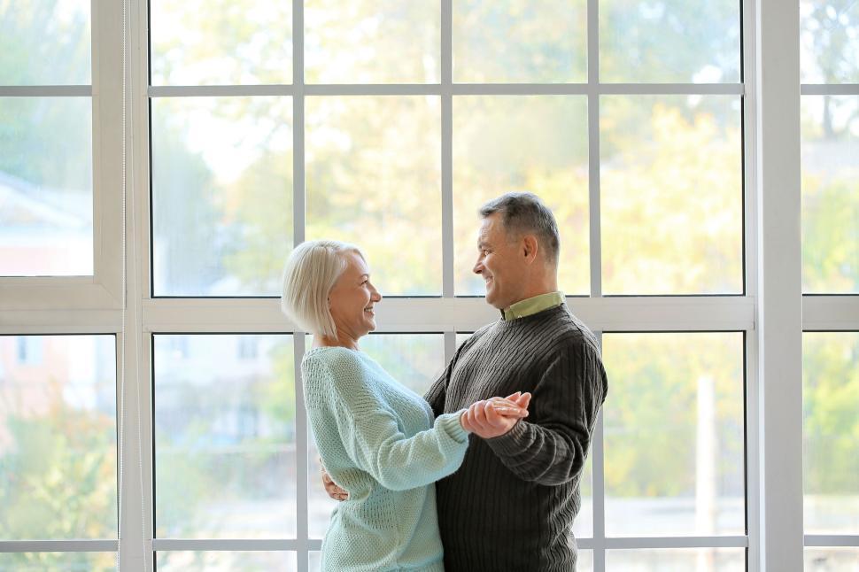 Free Image of Elderly couple sharing a serene dance by the windows 