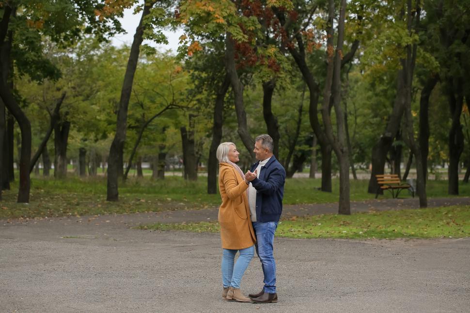Free Image of Elderly couple dancing outdoors in a lush park 