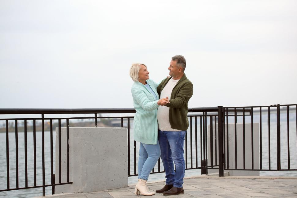 Free Image of Elderly couple dancing by the waterfront railing 