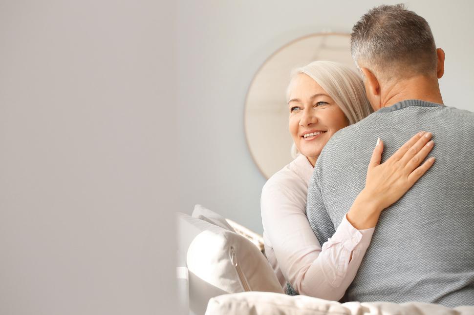 Free Image of Older couple hugging and smiling in their cozy home. 