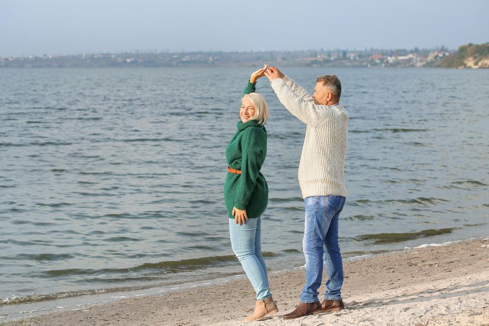 Free Image of Older couple dancing together on the beach at sunset. 