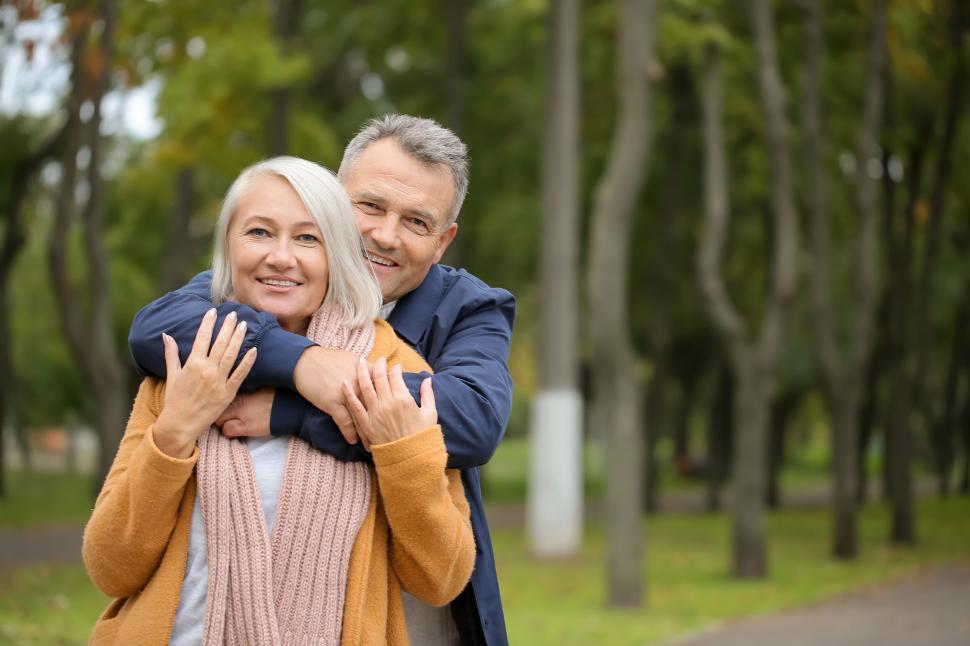 Free Image of Older couple happily enjoying a hug in park together. 