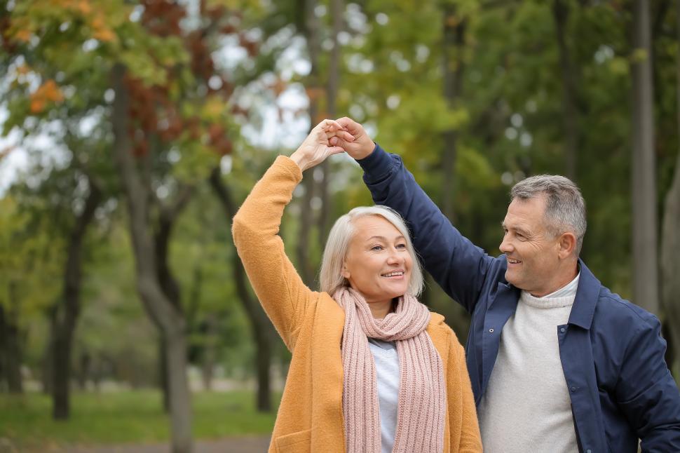 Free Image of Older couple dancing and smiling in a green park area. 