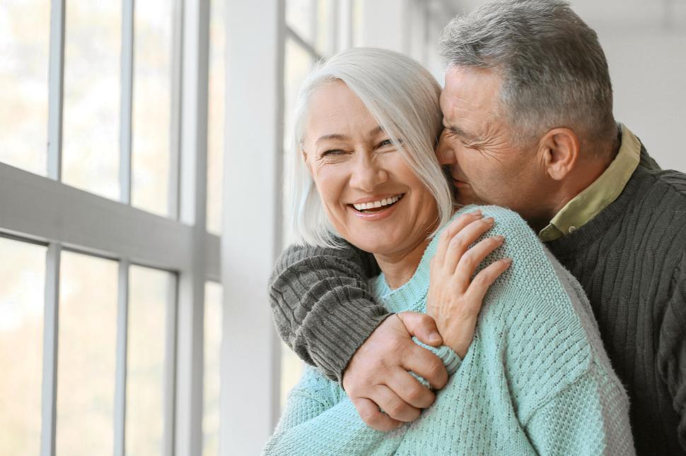 Free Image of Joyful older couple hugging and laughing in bright room. 