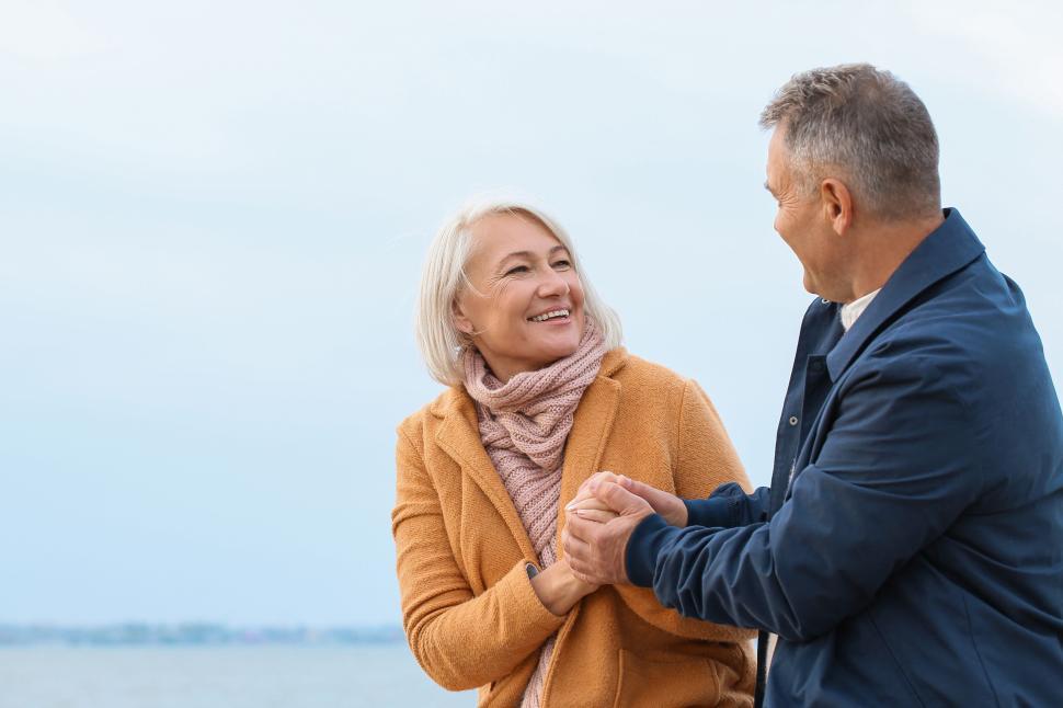 Free Image of Elderly couple holding hands by the sea shore. 