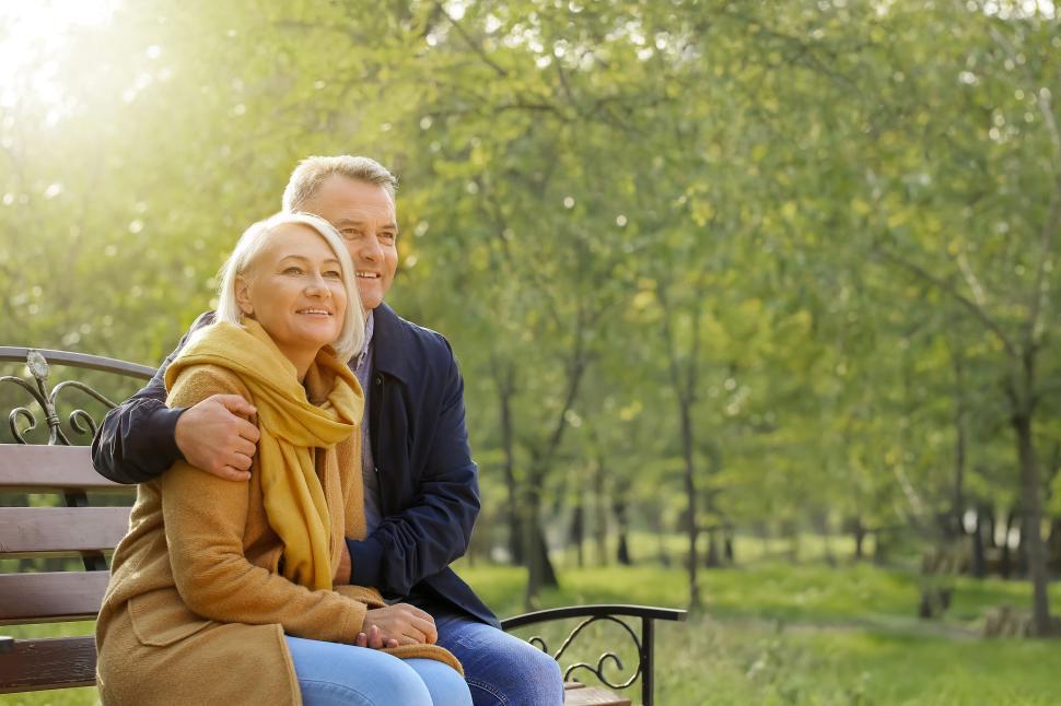 Free Image of Elderly couple sitting on bench in green park. 