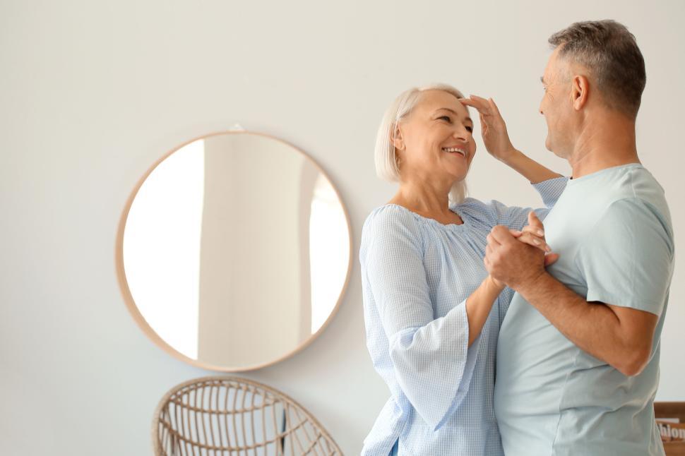 Free Image of Smiling couple dancing indoors by the mirror. 