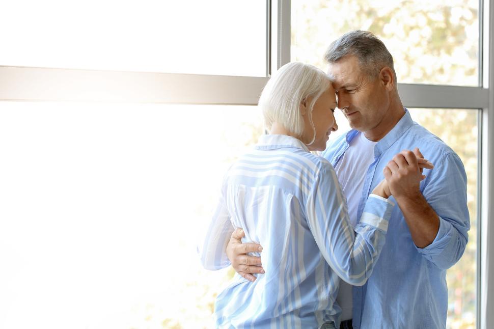 Free Image of Elderly couple dancing in front of large window 