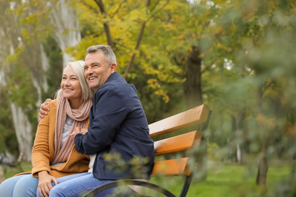 Free Image of Elderly couple hugging on park bench in fall. 
