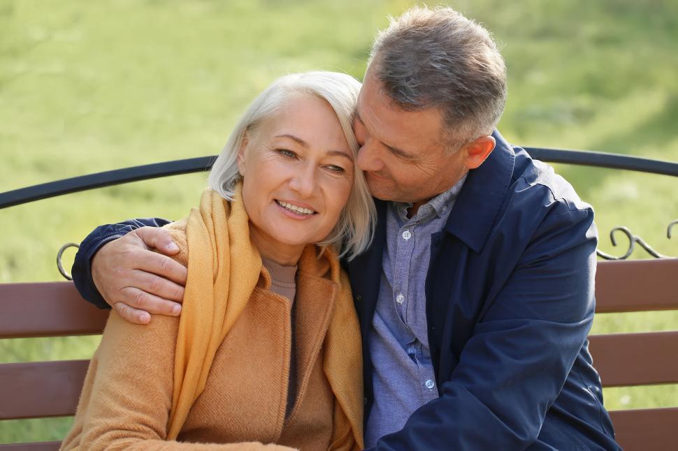 Free Image of Elderly couple embraces with love on wooden bench. 