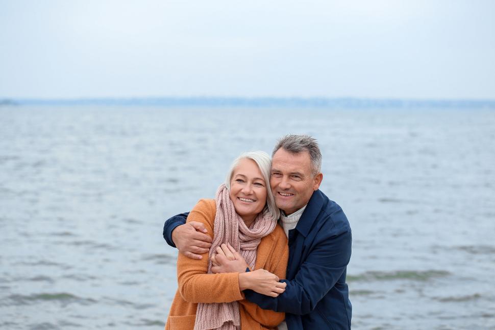 Free Image of Happy elderly couple embracing by the sea water. 