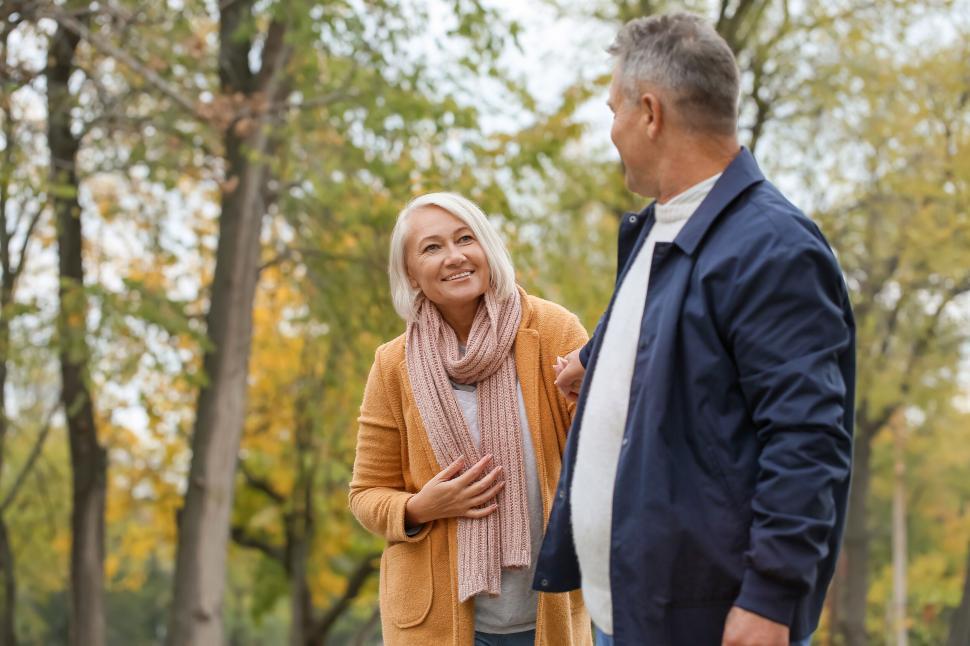 Free Image of Older couple walks in park during autumn, smiling warmly. 