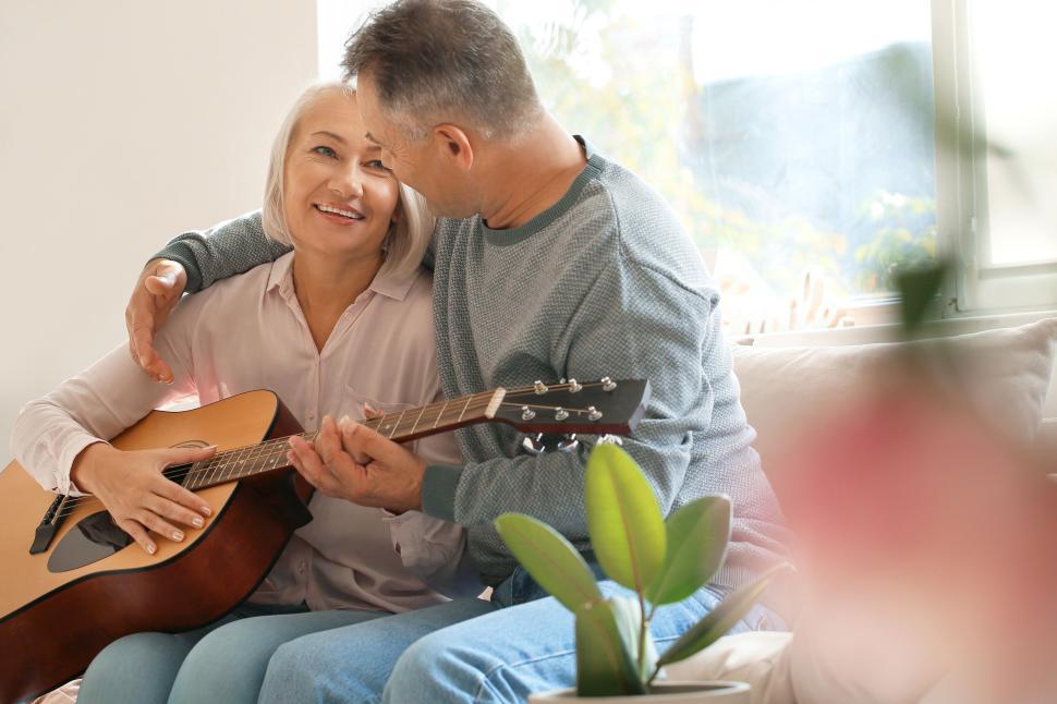 Free Image of Senior couple bonding with a guitar by the window. 