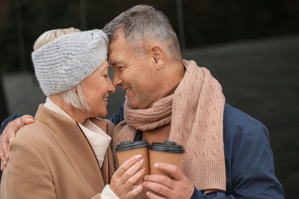 Free Image of Couple sharing hot drinks outdoors in cold weather 