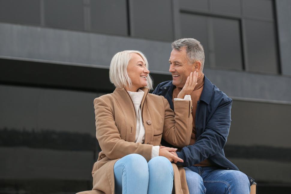 Free Image of Couple sitting outdoors, embracing on a chilly day. 