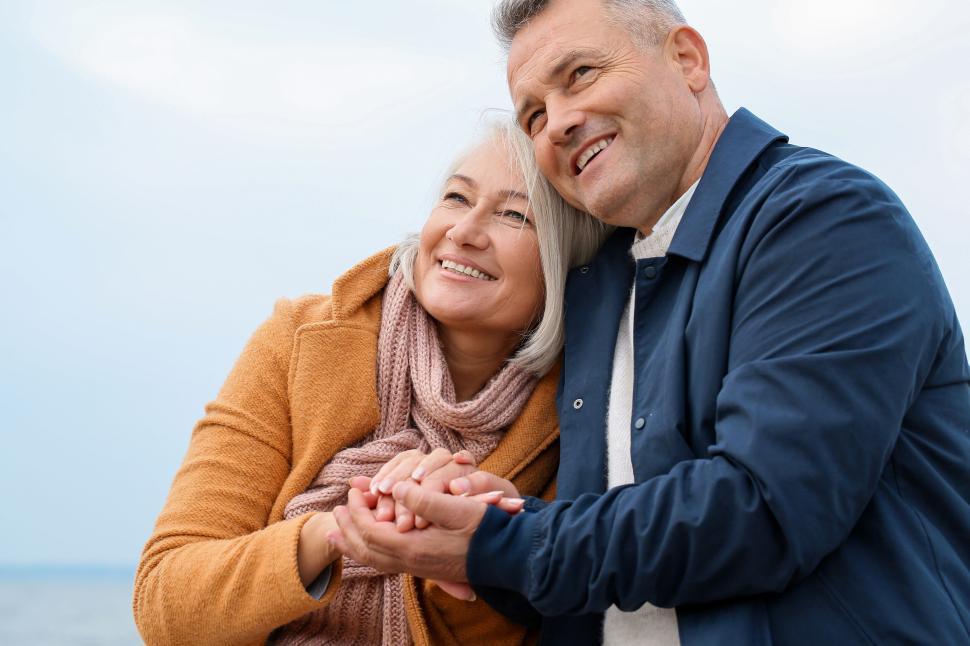 Free Image of Couple near beachside, smiling and holding hands warmly. 