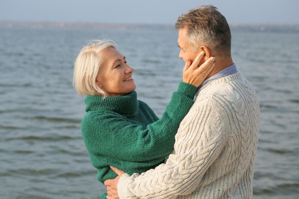 Free Image of Couple in sweaters share a moment by the water 