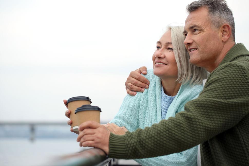 Free Image of Senior couple holding takeaway coffee by the riverside 