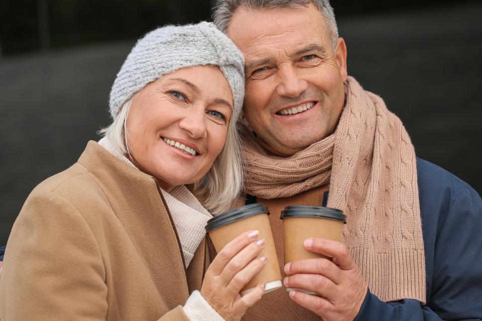 Free Image of Elderly couple toasting with coffee cups in winter 