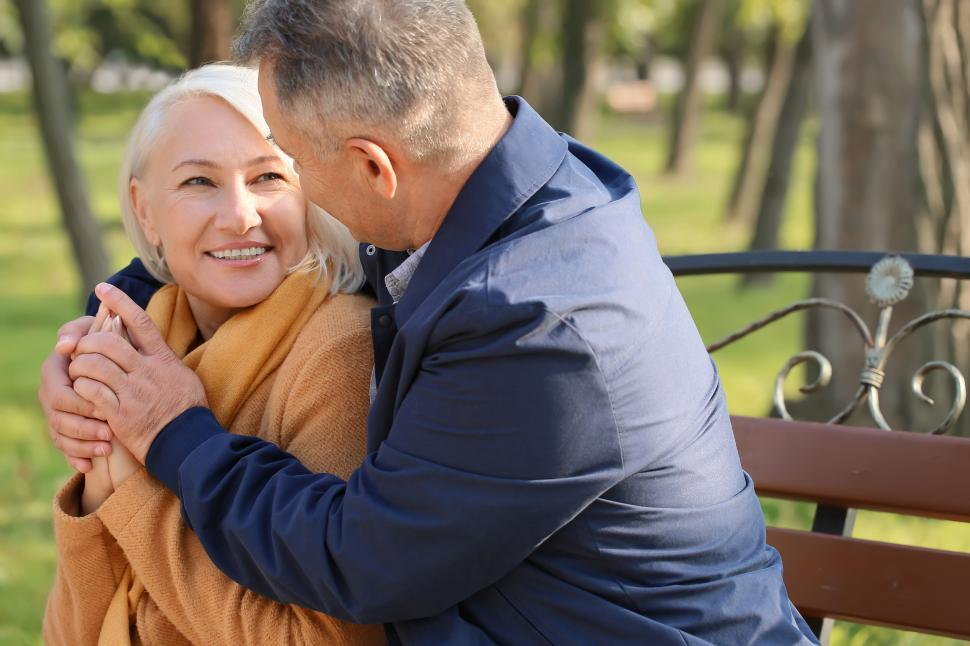Free Image of Elderly couple cuddling on a park bench in autumn 