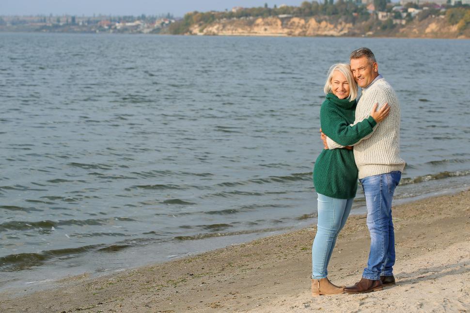 Free Image of Elderly couple hugging by a serene beachfront landscape 